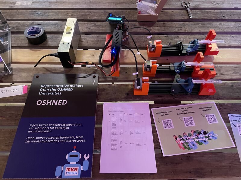 Open-source syringe pumps built from 3D printer parts, beside an OSHNED sign: open-source research hardware, from lab robots to batteries and microscopes.