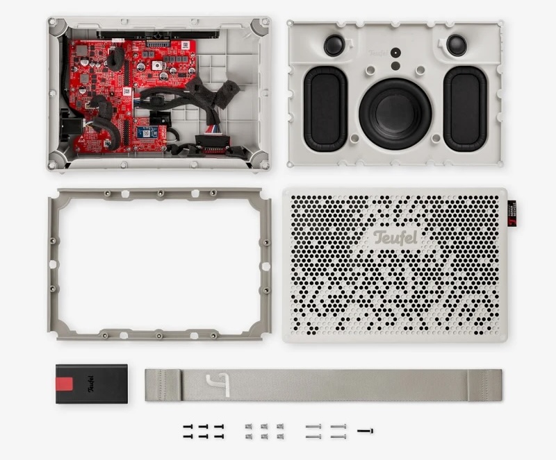 A Teufel Bluetooth speaker laid out as separable parts: housing, grille, drivers, circuit board, strap, and screws.